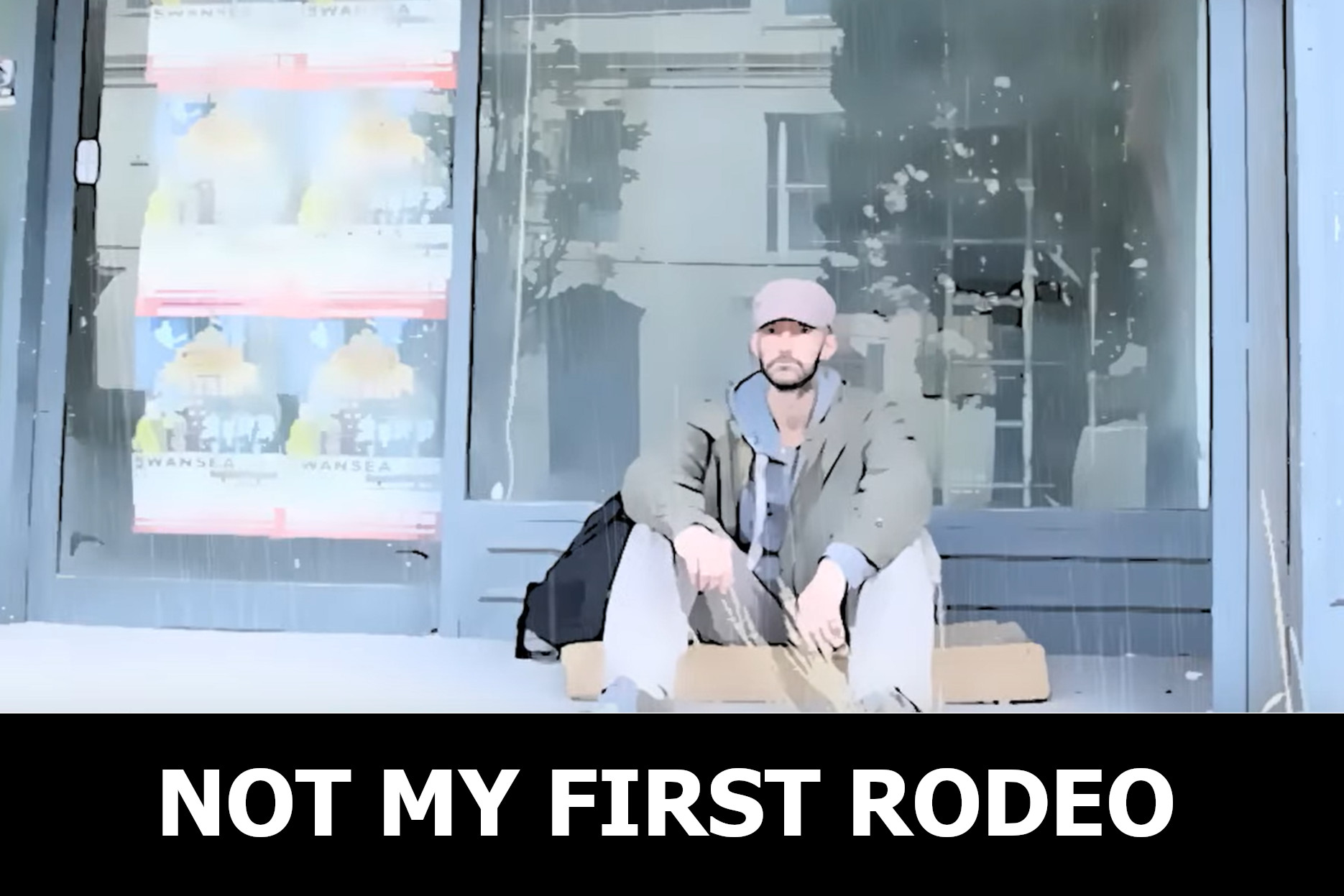 A man sits in front of a shop on a cardboard box