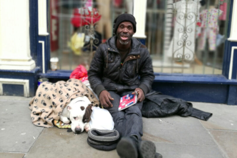 A smiling man sits on the pavement